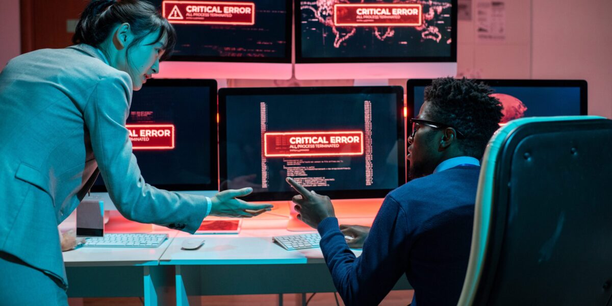 Technology systems at a business are reading an error code, while 2 intelligent people are working to get to the root of the cyber security problem.